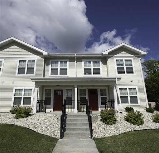 A two-story house with a red door and a front porch.