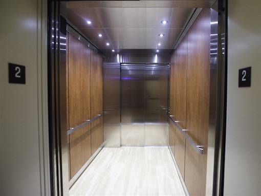 A long hallway with wood panels and elevator doors on either side.