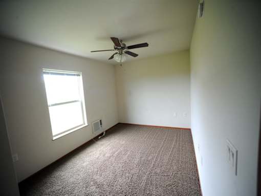 A room with a ceiling fan and a window.