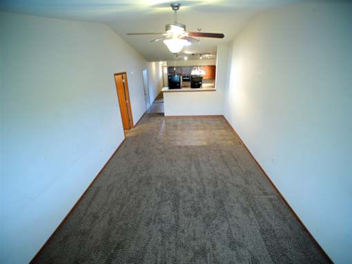 A long hallway with a carpeted floor and a ceiling fan.