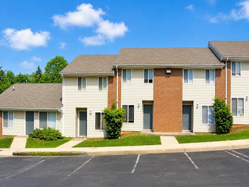 A row of townhouses with a parking lot in front.