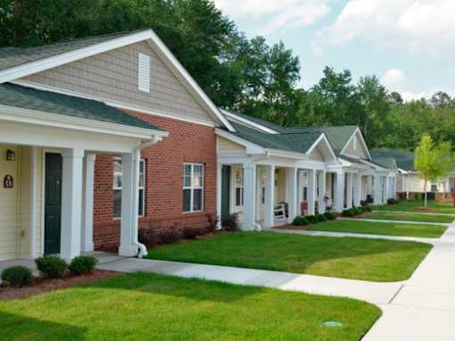 a row of houses with white pillars and green grass