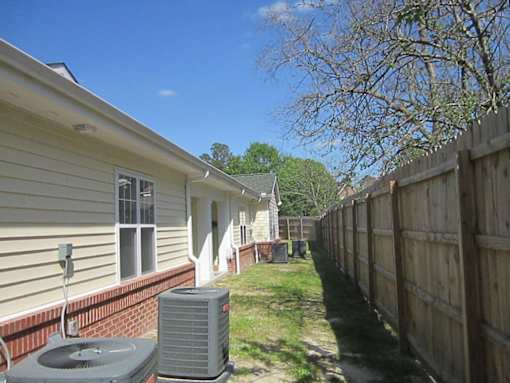 the side of a house with a yard and a wooden fence