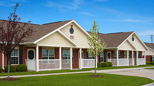 A small house with a brown roof and a white fence.