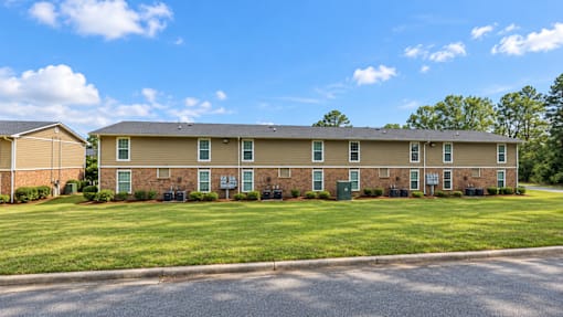 Apartment complex with a grassy front yard and a clear blue sky.