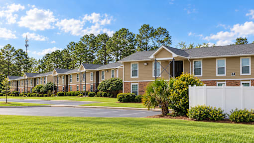 A row of houses with a white fence in front.