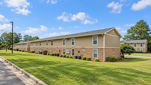 A long brick building with a green lawn in front.