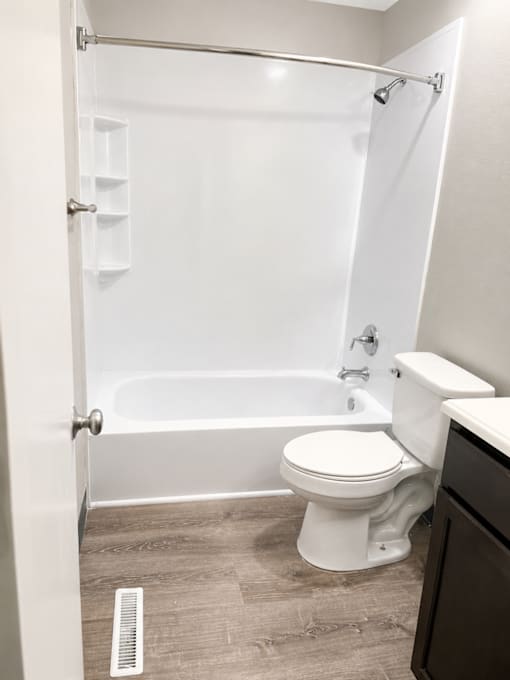 A white toilet sits next to a bathtub in a bathroom.