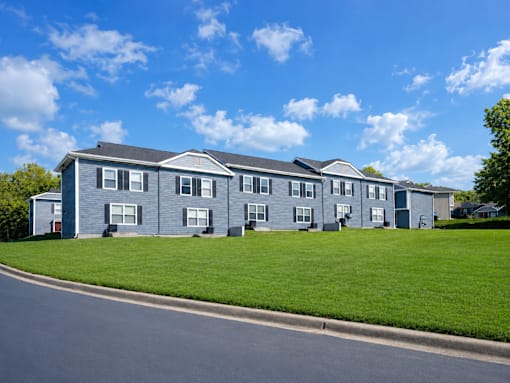 A row of houses with a blue sky and clouds in the background.