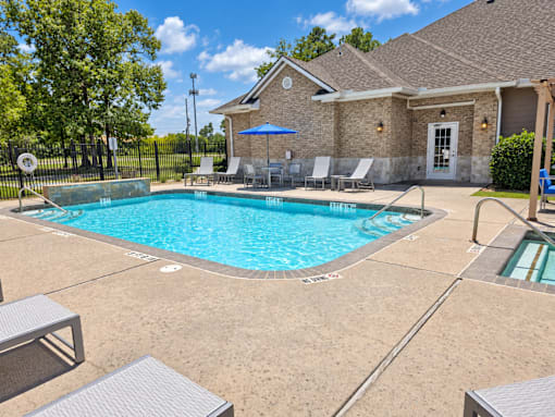 A pool with a blue umbrella and chairs around it.