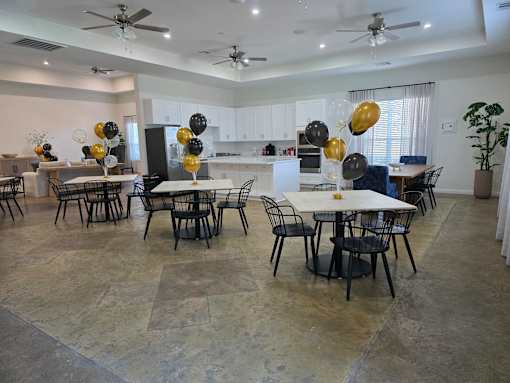 A dining room with a table surrounded by chairs and balloons.