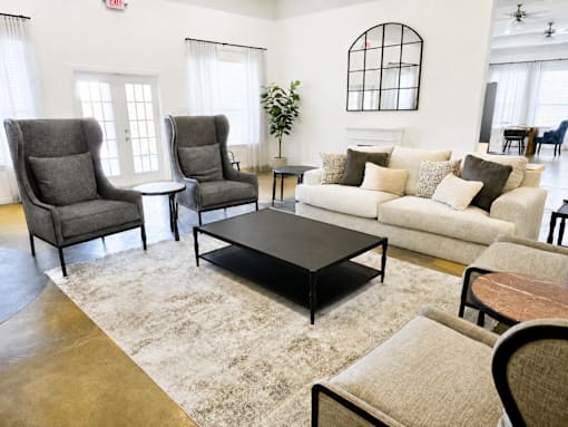 A living room with a grey sofa, two grey armchairs, a black coffee table, and a rug.