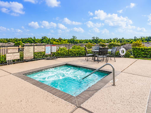 A hot tub sits in the middle of a patio surrounded by a fence.