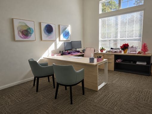 A room with a desk, chairs, and artwork on the wall.