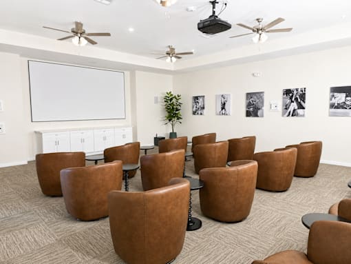 A room with brown chairs and a white screen on the wall.