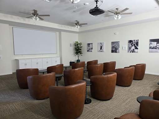 A room with brown chairs and a white screen on the wall.