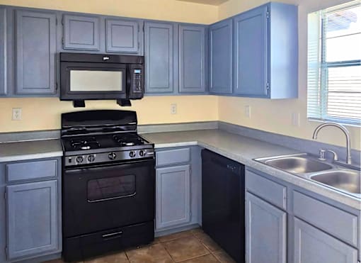 A kitchen with a black stove and cabinets.