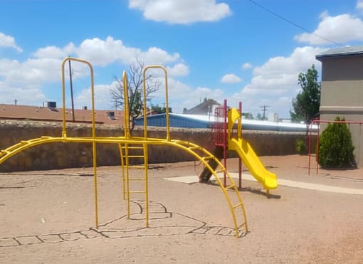 A playground with a yellow slide and climbing frame.