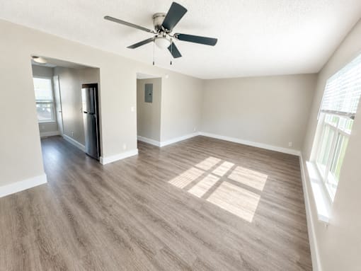 A spacious room with a ceiling fan and a refrigerator.