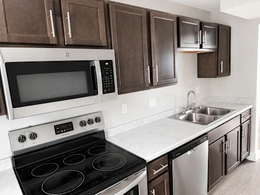 A modern kitchen with dark brown cabinets and stainless steel appliances.