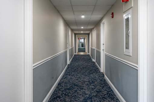 A long hallway with a carpeted floor and white walls.