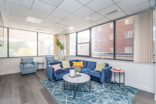 a living room with blue couches and a coffee table in front of large windows