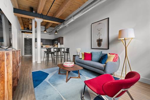 A living room with a red chair and a grey couch.