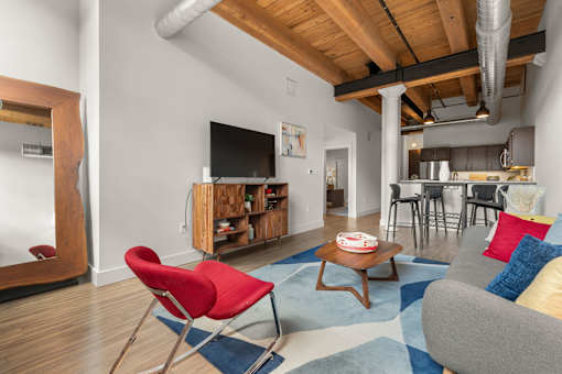 A living room with a red chair and a grey couch.