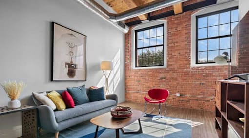 A living room with a grey couch, a red chair, and a blue rug.