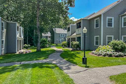 A sunny day in a quiet residential area with apartment buildings and a tree-lined street.