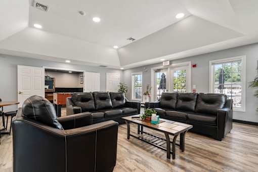 A black leather couch in a room with wooden floors and white walls.