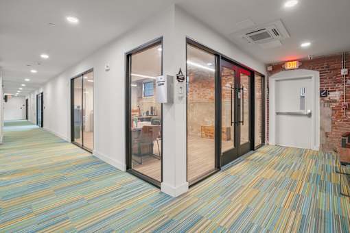A hallway with a carpeted floor and glass doors.