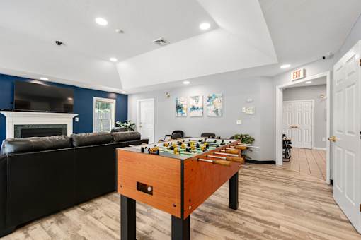 A room with a black couch and a wooden table with a chess set on it.