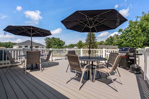 A wooden deck with a table and chairs under umbrellas.
