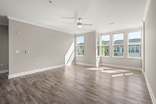 A room with a ceiling fan and wooden flooring.