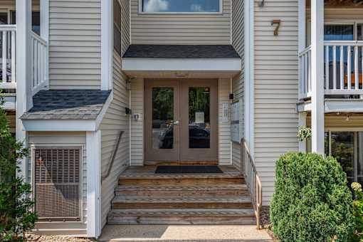 A house number 7 with a brown door and steps leading to it.