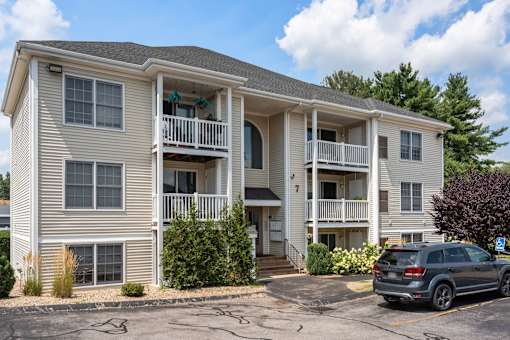 A two-story apartment building with a car parked in front.
