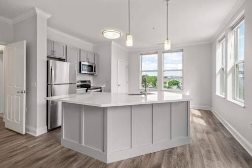 A kitchen with white cabinets and a wooden floor.