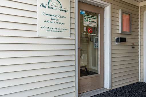 A sign on a building reads Old Towne Village Community Center Hours 6:00 am - 11:00 pm under 16 years of age requires adult supervision.