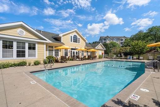 A swimming pool in front of a yellow house.