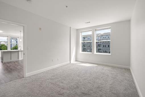 A spacious, empty room with a carpeted floor and two windows.