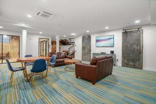 A room with a blue and yellow carpet and a brown couch.