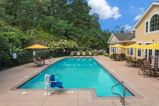 A swimming pool surrounded by trees and a yellow building.