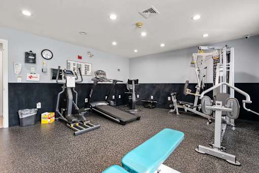 A gym with a variety of equipment including a treadmill, weights, and a bench.