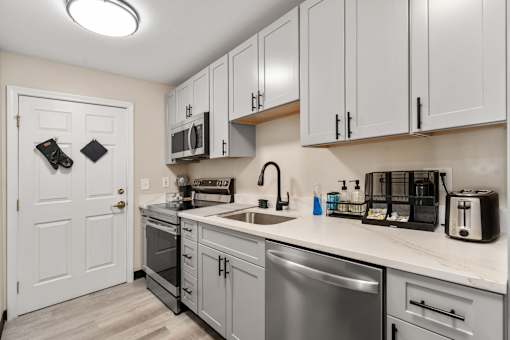 A kitchen with a white door and a stainless steel dishwasher.