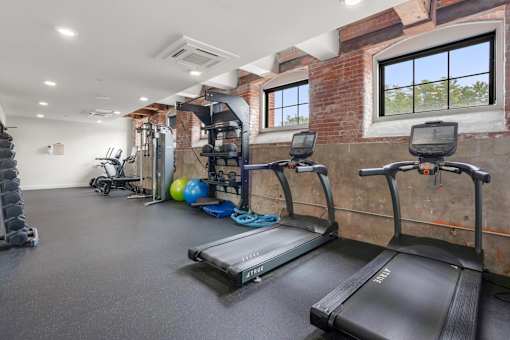 A gym with treadmills, weights, and exercise equipment.