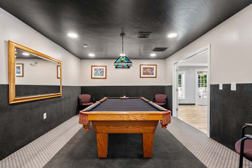 A pool table in a room with a mirror on the wall.