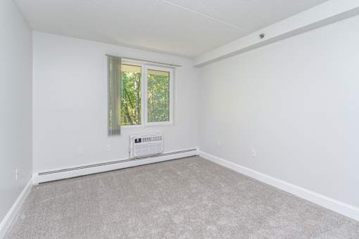 an empty living room with white walls and a window