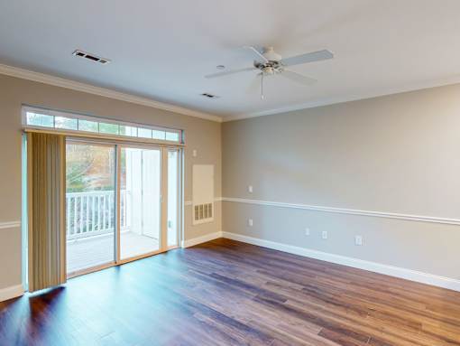 A room with a ceiling fan and sliding glass doors.