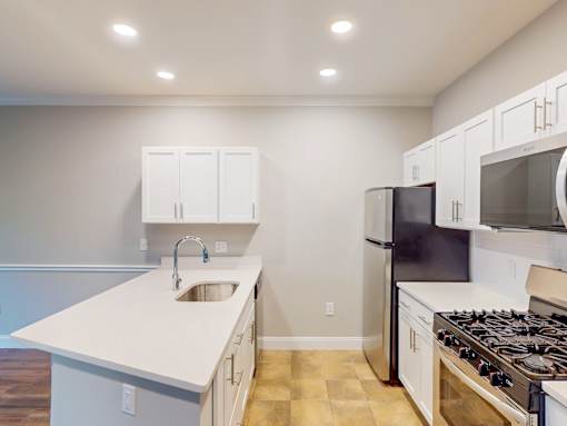 A kitchen with white cabinets and a black refrigerator.